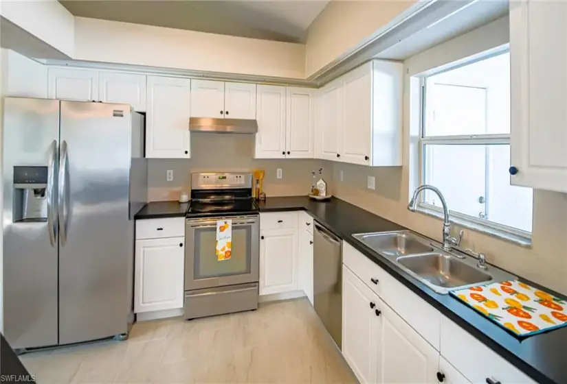 Kitchen with appliances with stainless steel finishes, sink, and white cabinets