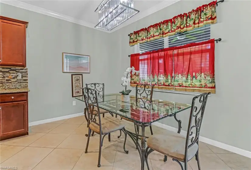 Dining room featuring a notable chandelier, crown molding, and light tile floors