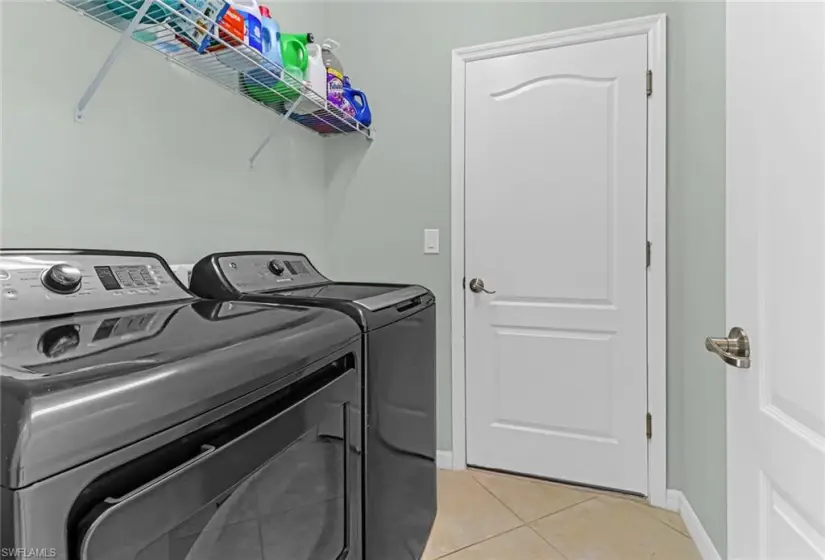 Laundry area with independent washer and dryer and light tile floors