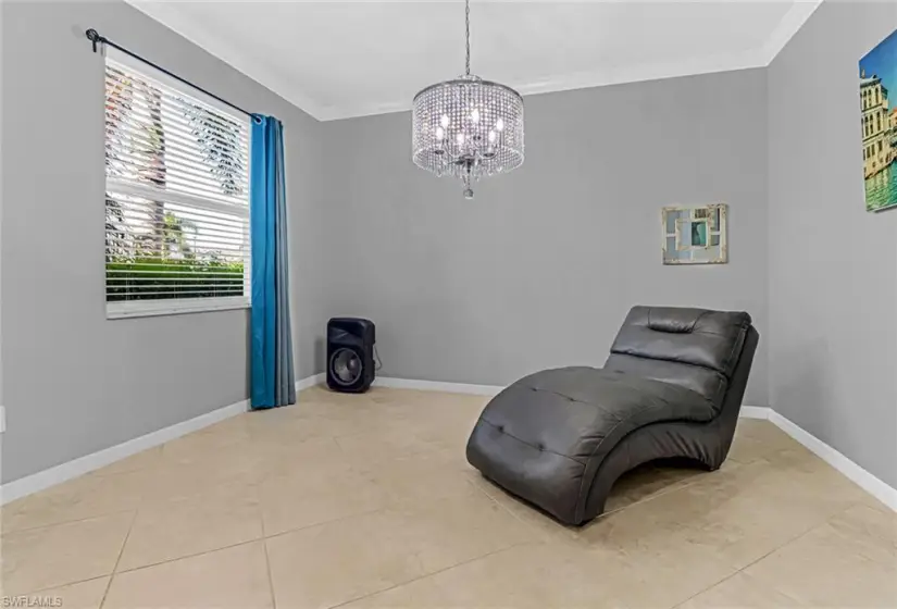 Sitting room with tile floors, an inviting chandelier, and crown molding