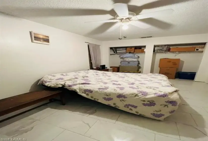 Tiled bedroom featuring ceiling fan and a textured ceiling