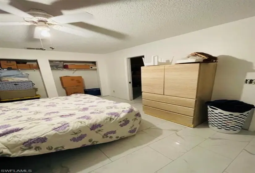 Bedroom with tile flooring, ceiling fan, and a textured ceiling